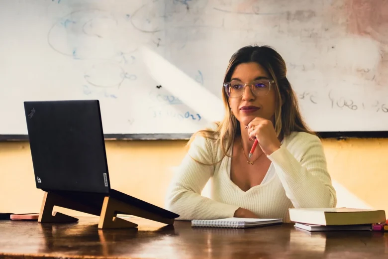 Caderno aberto com anotações de instruções ao lado de um laptop, representando a escrita de prompts organizados