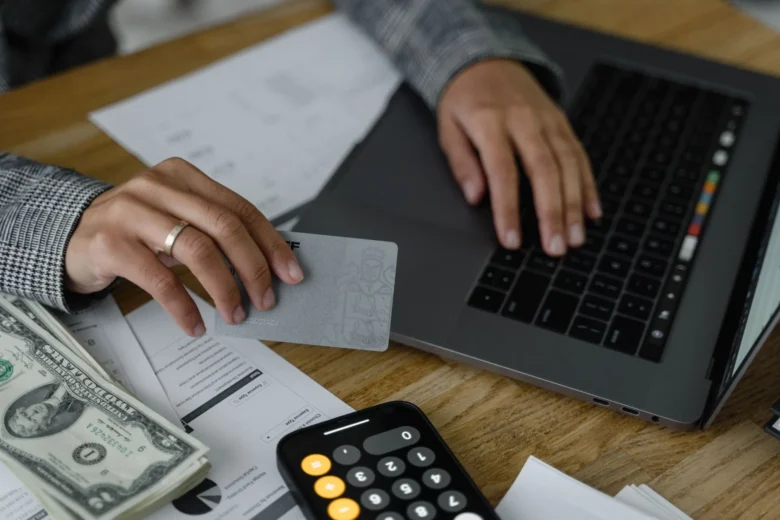 Pessoa comparando planos de assinatura de IA em um laptop, com cartão de crédito sobre a mesa