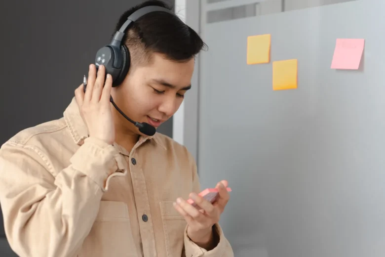 Estudante com fones de ouvido pratica conversação em outro idioma usando um aplicativo de voz com IA no celular
